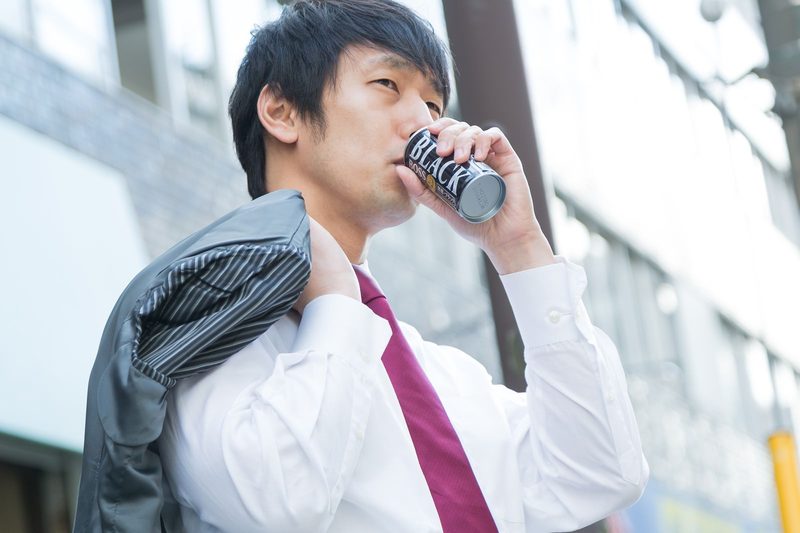 缶コーヒーを飲む会社員